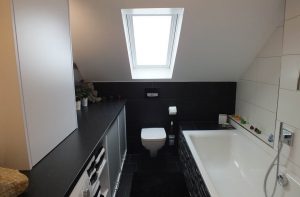 Blick in ein neu umgebautes Badezimmer mit WC unter der Dachschräge und einer Badewanne