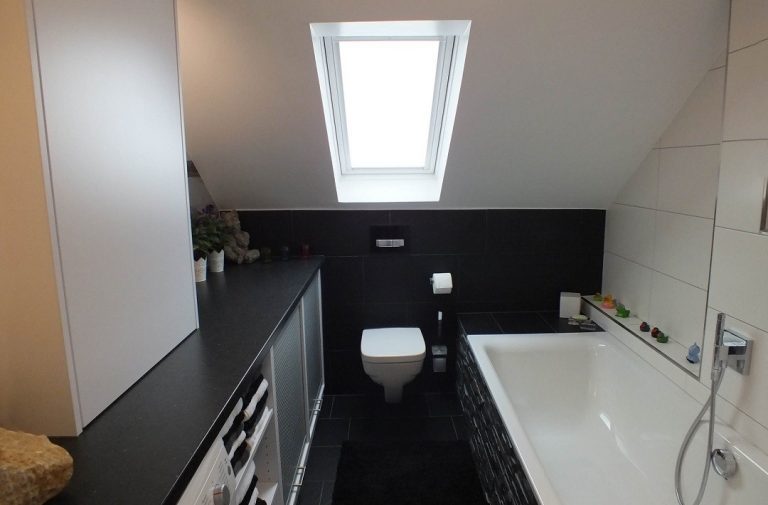 Blick in ein neu umgebautes Badezimmer mit WC unter der Dachschräge und einer Badewanne